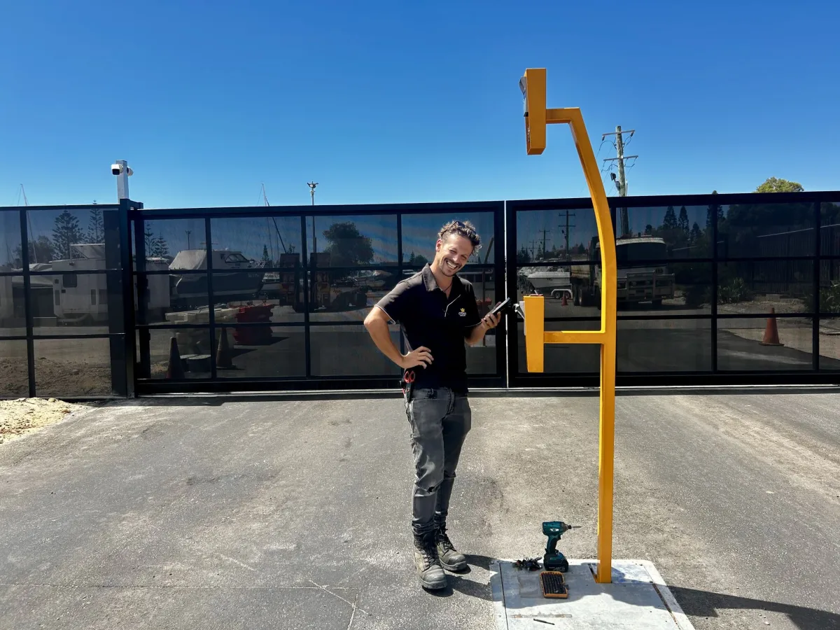 Security technician conducting an on-site security assessment next to a newly installed access control post and perimeter fence